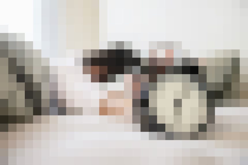 People sitting on a sofa in a bright living room; faces are indistinct due to blur.