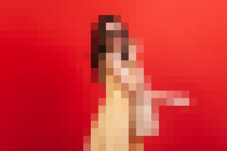 Performer standing on a bright red background wearing light-colored clothing, facing the camera.