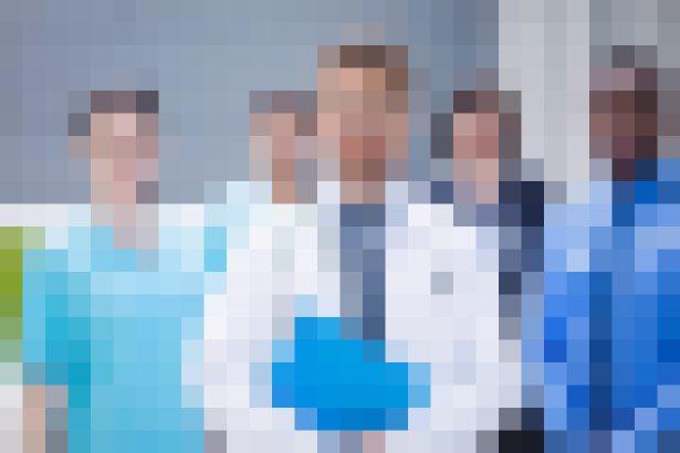 Group of healthcare professionals in white coats posing for a team photo in a clinical setting