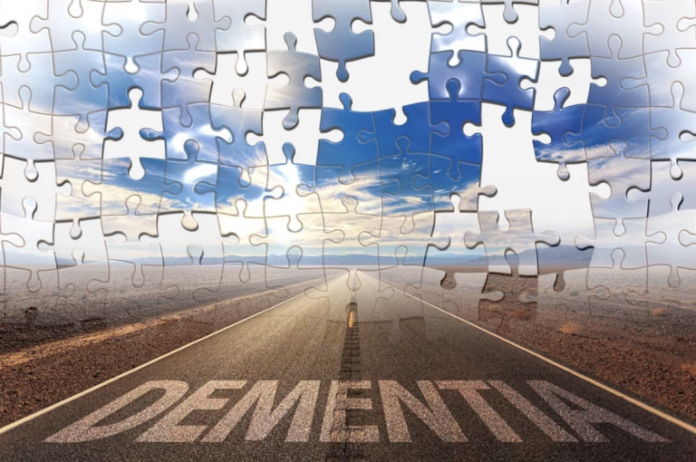 Road to dementia: a straight highway marked 'DEMENTIA' under a cloudy sky with puzzle pieces overlaying the image.